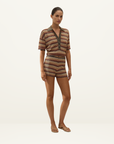 Model wearing a Faithfull Raya polo top in Lais stripe crochet-knit with a collared neckline and matching shorts.