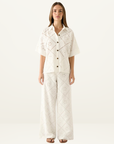 White Esmaee shirt featuring intricate eyelet embroidery, a button-down front, and a relaxed, short-sleeved silhouette.