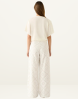 Esmaee white wide-leg pants featuring intricate floral eyelet embroidery and a high-waisted silhouette.