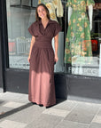 Woman wearing a chocolate brown Sovere Lyra midi dress with magyar sleeves, pleated waistband, and full skirt.