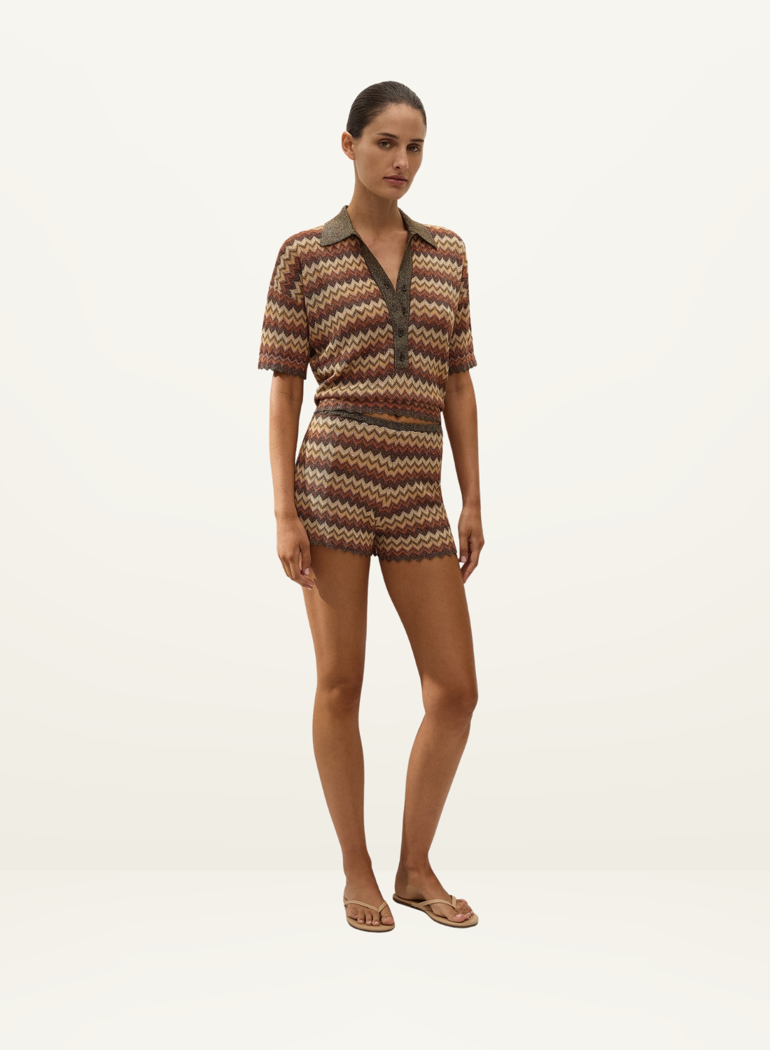 Model wearing a Faithfull Raya polo top in Lais stripe crochet-knit with a collared neckline and matching shorts.