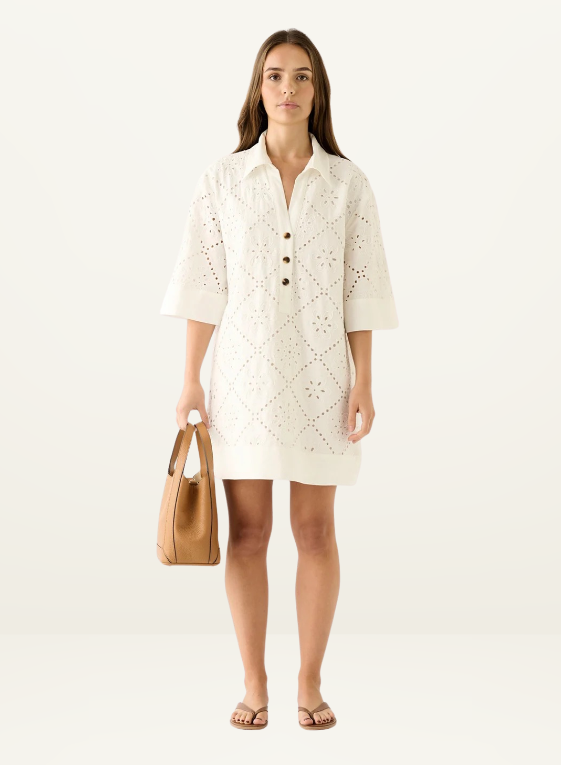 Model wearing a white mini shirt dress in eyelet embroidery fabric with a button-down collar and elbow-length sleeves.