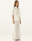 White Esmaee button-down shirt featuring intricate eyelet embroidery, a classic collar, and short sleeves.