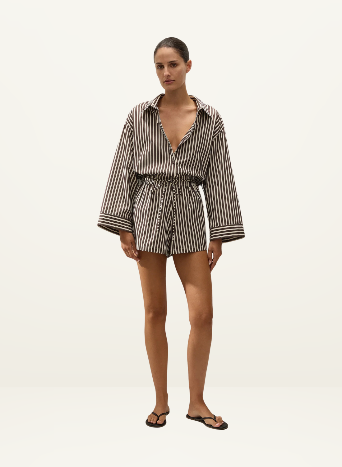 Faithfull Belas cotton playsuit in Rita stripe port with oversized long sleeves, collared neckline, and drawstring waist.