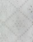 White cotton fabric featuring intricate floral eyelet embroidery in a geometric diamond pattern.
