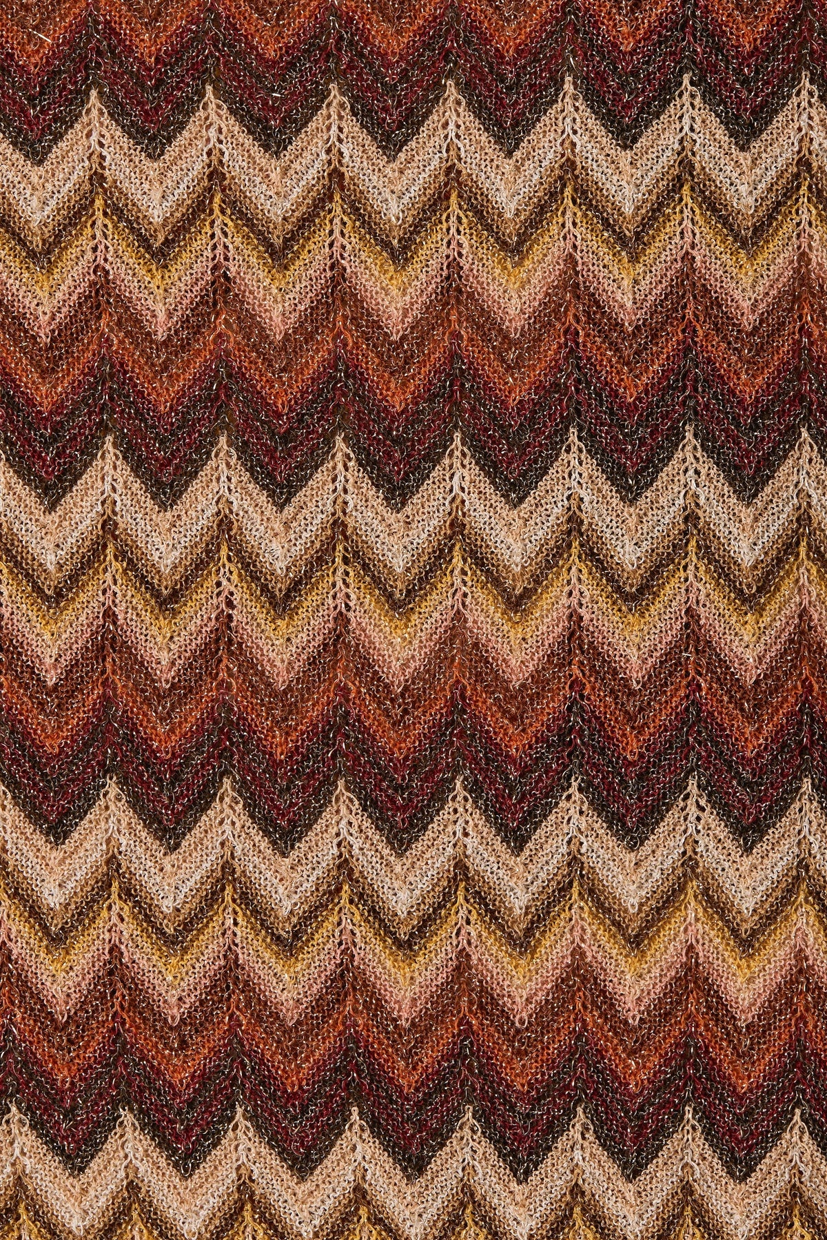 Close-up of Faithfull Raya polo knit fabric featuring a multi-colored chevron stripe pattern in warm earth tones.