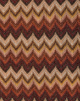 Close-up of Faithfull Raya polo knit fabric featuring a multi-colored chevron stripe pattern in warm earth tones.